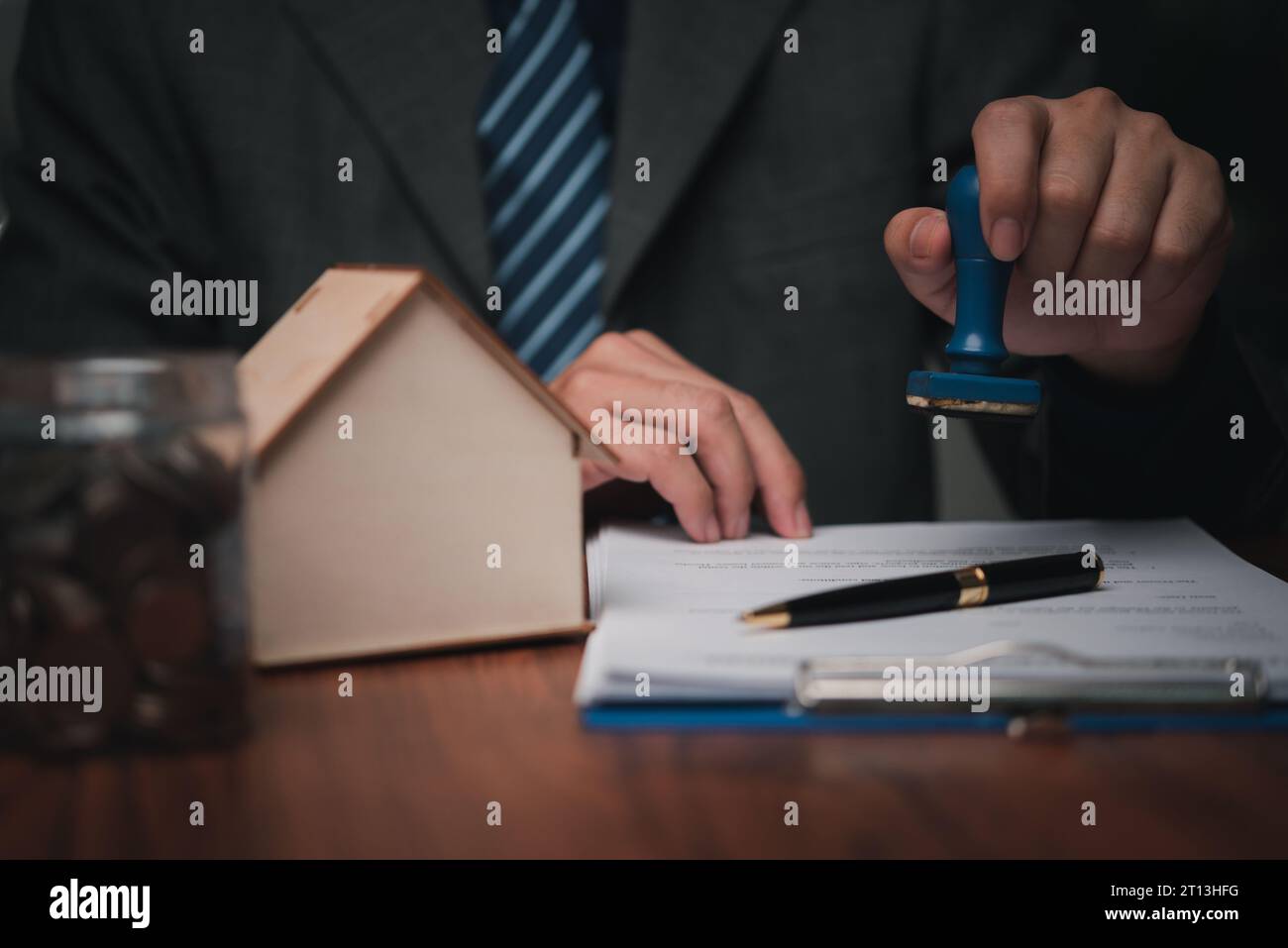 agent immobilier avec maison. Personne d'affaires détenant un timbre approuvé sur le contrat de prêt hypothécaire document plan de maison sur la table. Banque D'Images