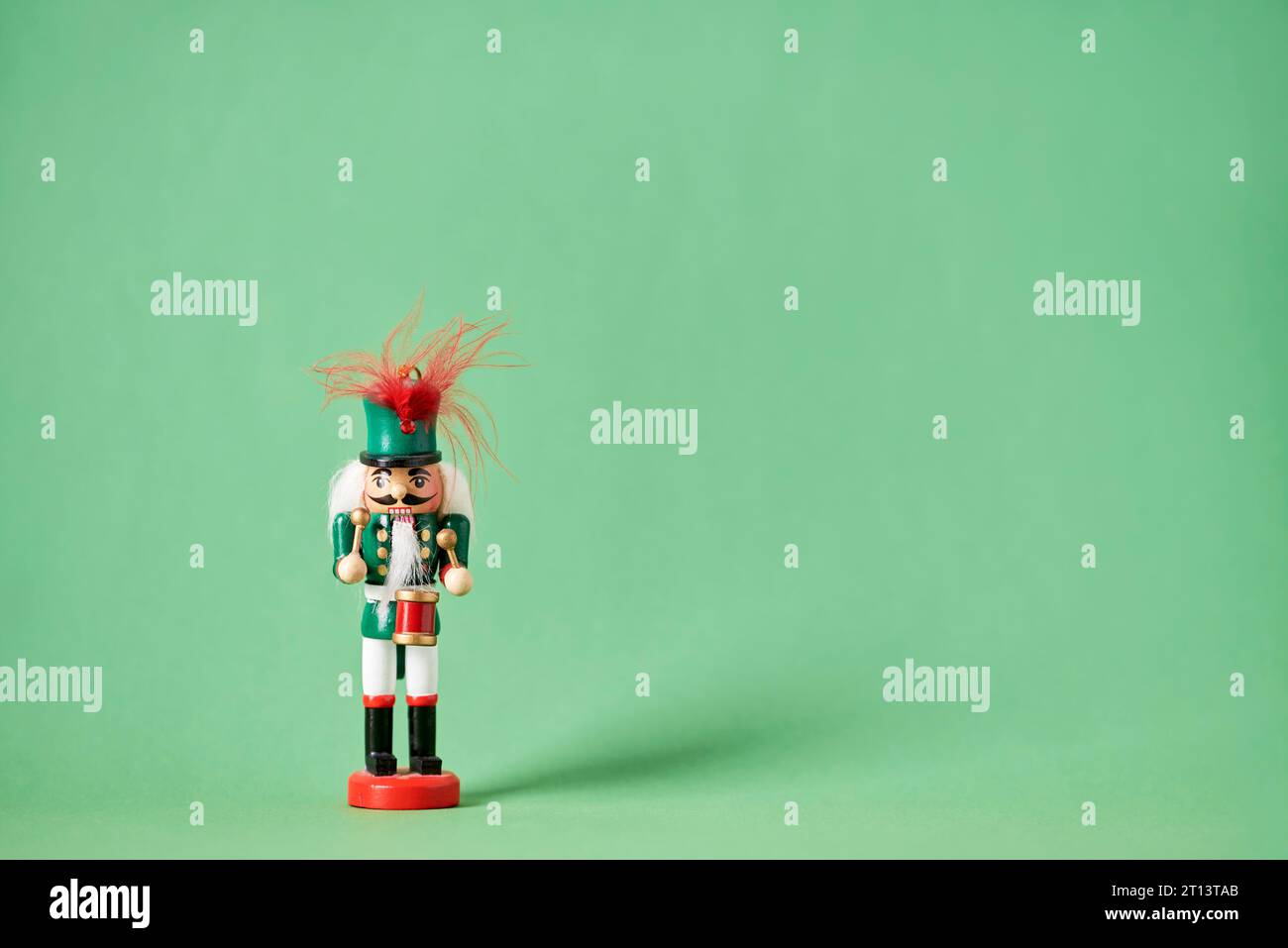 Casse-noisette de Noël traditionnel coloré en bois en costume vert avec un fond vert, composition minimale avec espace de copie. Banque D'Images