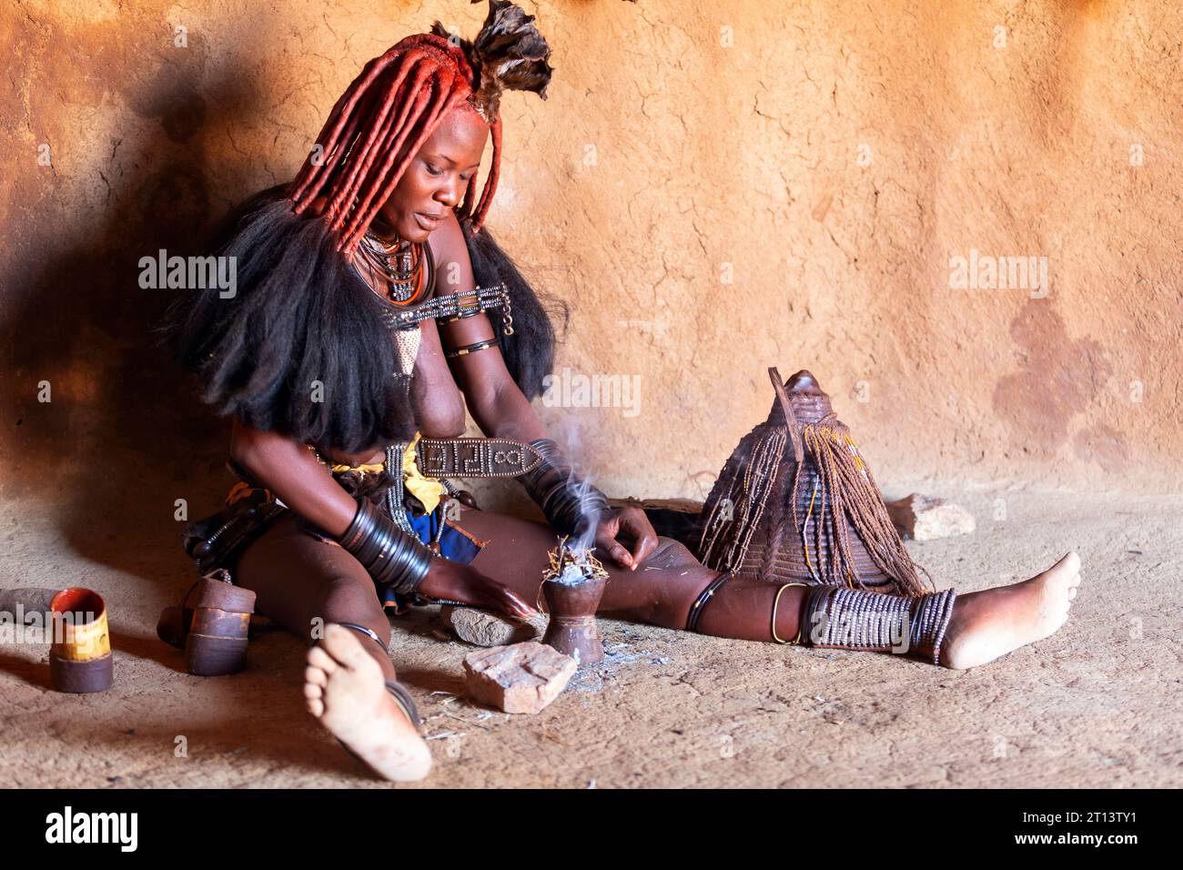 Namibie - 22 août 2023 : une femme Himba prend quotidiennement un bain de fumée à l'intérieur de sa cabane dans un village traditionnel Himba près de Kamanjab, Namibie, Afrique. Banque D'Images