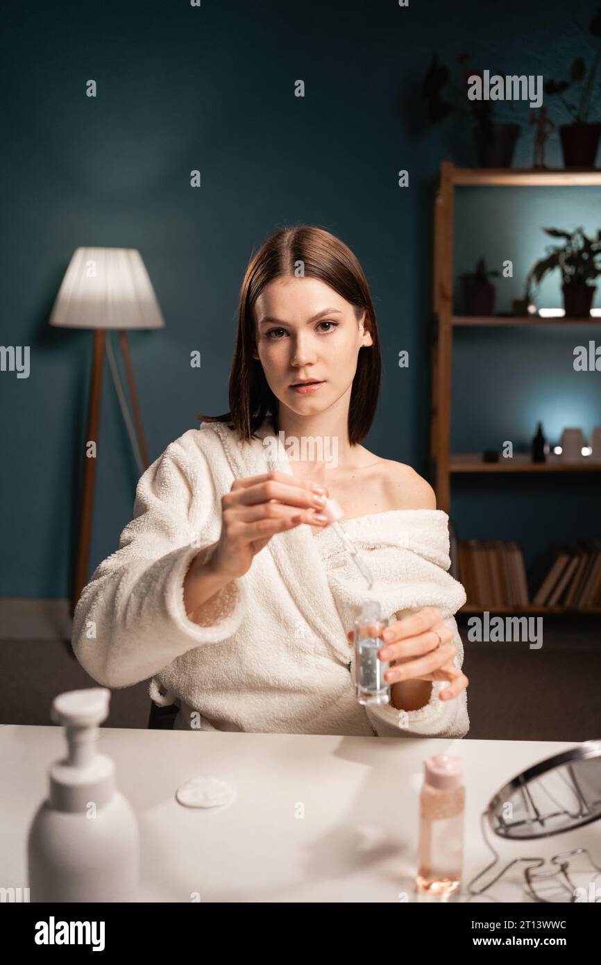 Femme blogueuse de beauté montrant des produits cosmétiques de soin de sérum à la caméra, l'enregistrement vidéo pour blog, la revue pour son produit de beauté. Espace de copie Banque D'Images