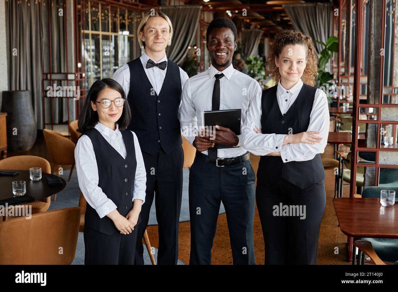 Portrait de groupe du personnel du restaurant avec des serveurs portant des uniformes classiques en noir et blanc et souriant à la caméra Banque D'Images