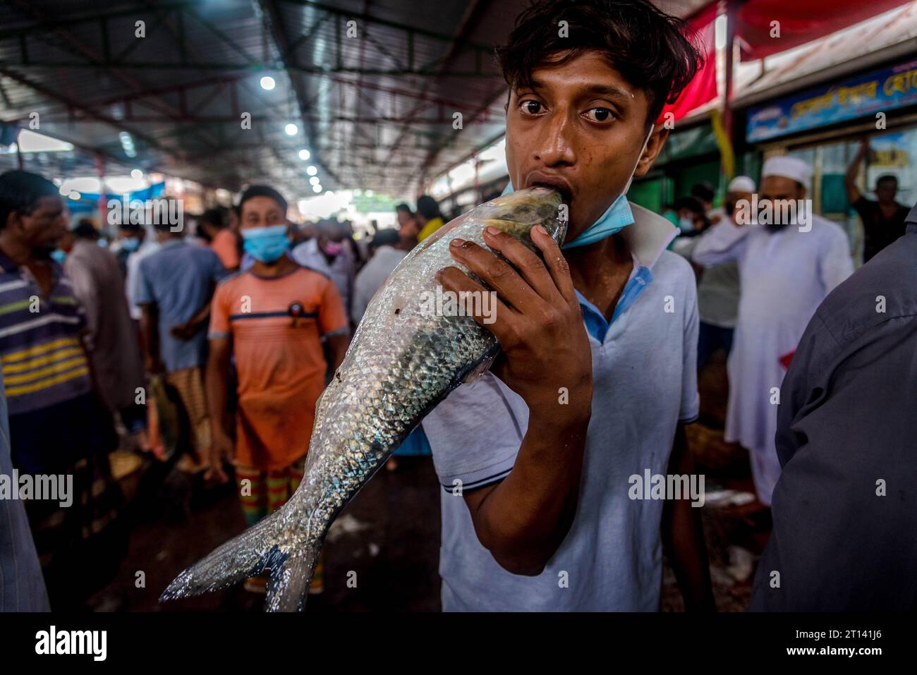 Un garçon pose pour une photo tout en s'amusant avec 'Elish Fish' dans sa bouche. Banque D'Images