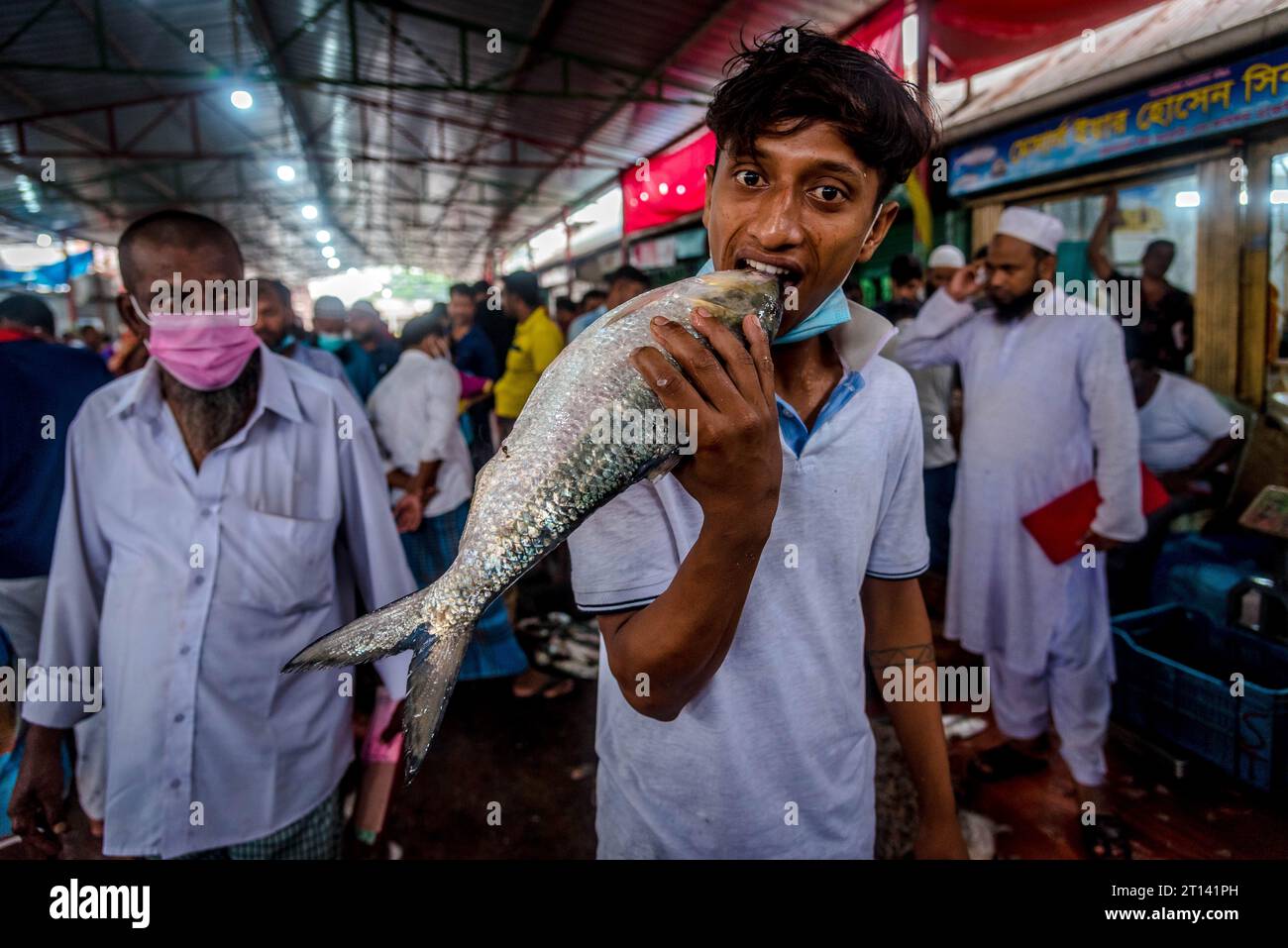 Un garçon pose pour une photo tout en s'amusant avec 'Elish Fish' dans sa bouche. Banque D'Images