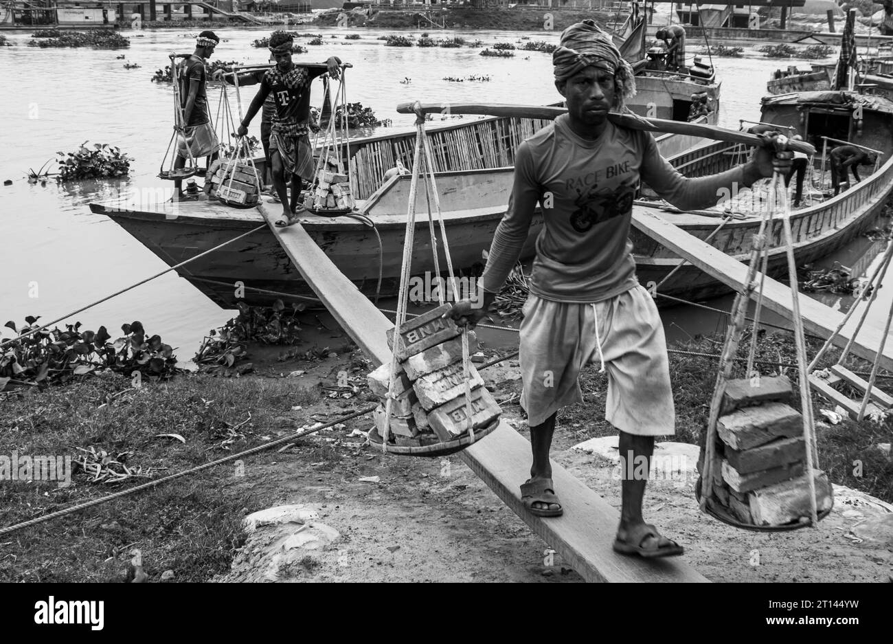 Les gens déchargent des briques du bateau, image capturée le 29 mai 2022, depuis Amen Bazar, au Bangladesh, où les travailleurs sont occupés à décharger des briques lourdes Banque D'Images