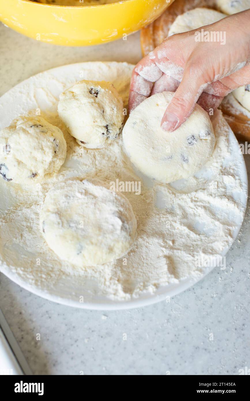 Mains féminines caucasiennes faisant des crêpes de fromage cottage avec fond de cuisson de raisins secs Banque D'Images