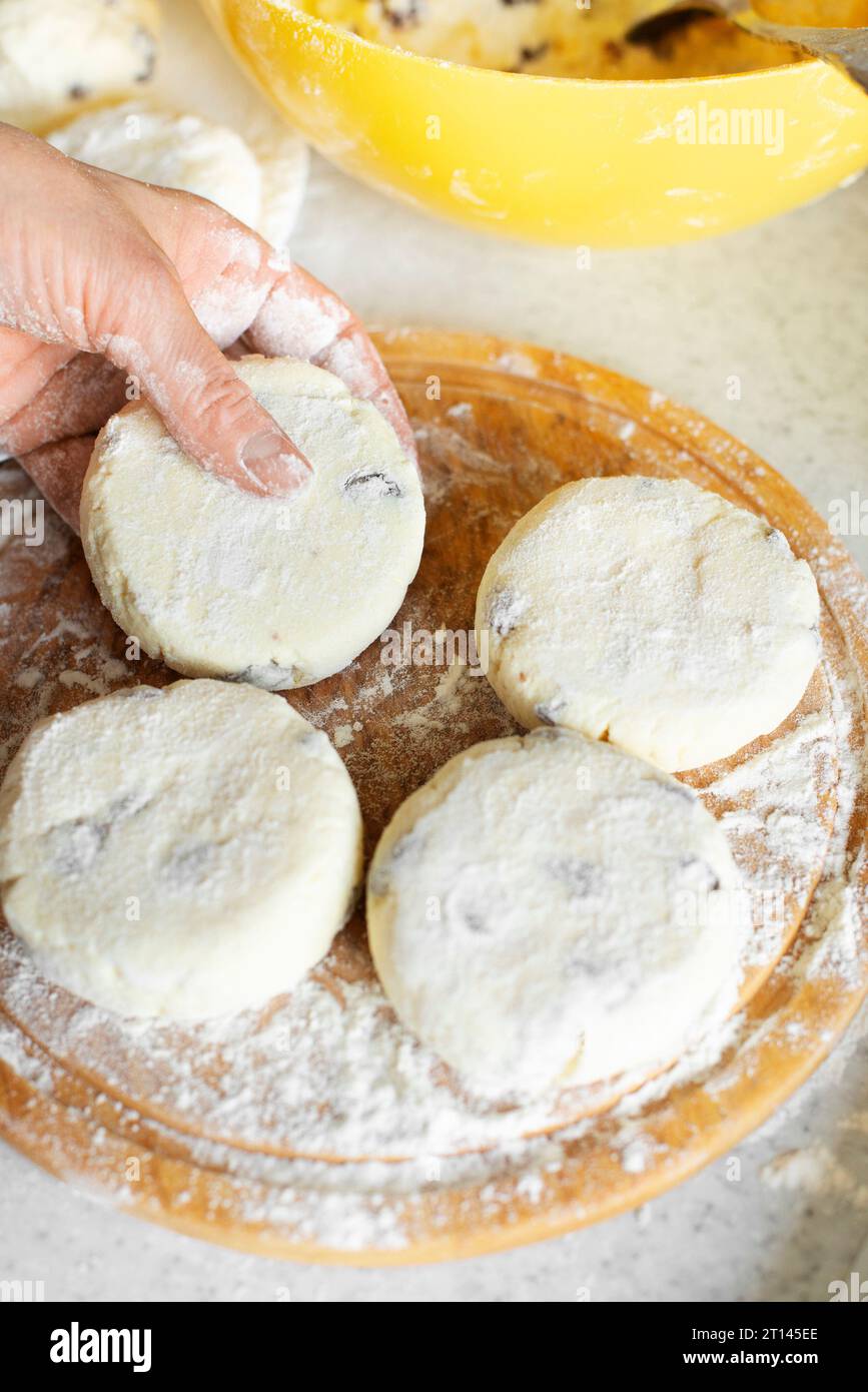 Mains féminines caucasiennes faisant des crêpes de fromage cottage avec fond de cuisson de raisins secs Banque D'Images