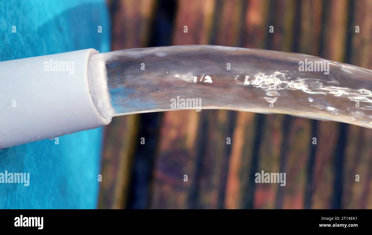 Jet d'eau s'écoule d'une piscine bleue sur une terrasse en bois. Banque D'Images