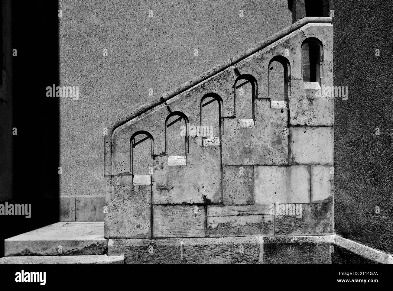 vieux vieux escalier extérieur en pierre patiné. balustrade en pierre. gros plan du mur de l'église. ouvertures poinçonnées arquées. architecture, voyages, tourisme. monochrome Banque D'Images