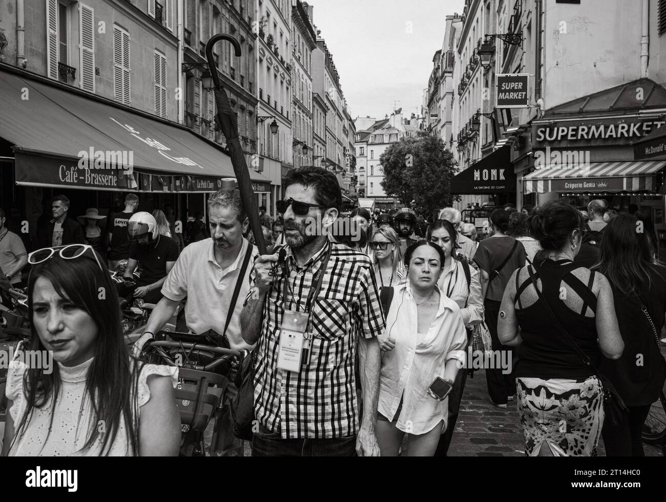 Un guide touristique tient un parapluie alors qu'il mène un groupe de touristes à travers le quartier Latin bondé de Paris, en France. Banque D'Images