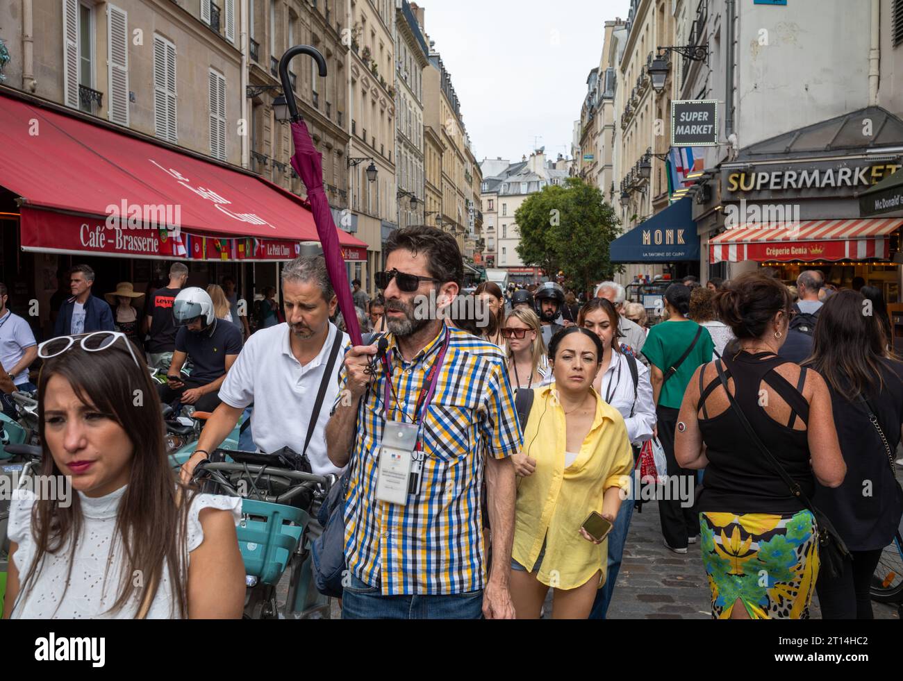 Un guide touristique tient un parapluie alors qu'il mène un groupe de touristes à travers le quartier Latin bondé de Paris, en France. Banque D'Images
