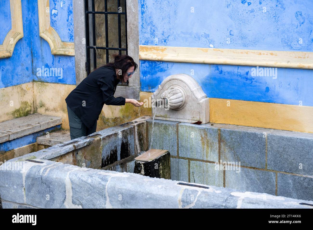 Une femme locale remplit des bouteilles d'eau en plastique à la fontaine Sabuga à Sintra Sintra Sintra est une ville et une municipalité dans la région du Grand Lisbonne au Portugal, Banque D'Images