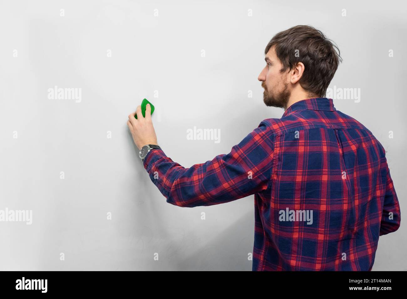 Jeune homme essuyant un tableau de conférence pour une présentation. Formation, entreprise, concept de démarrage d'entreprise Banque D'Images