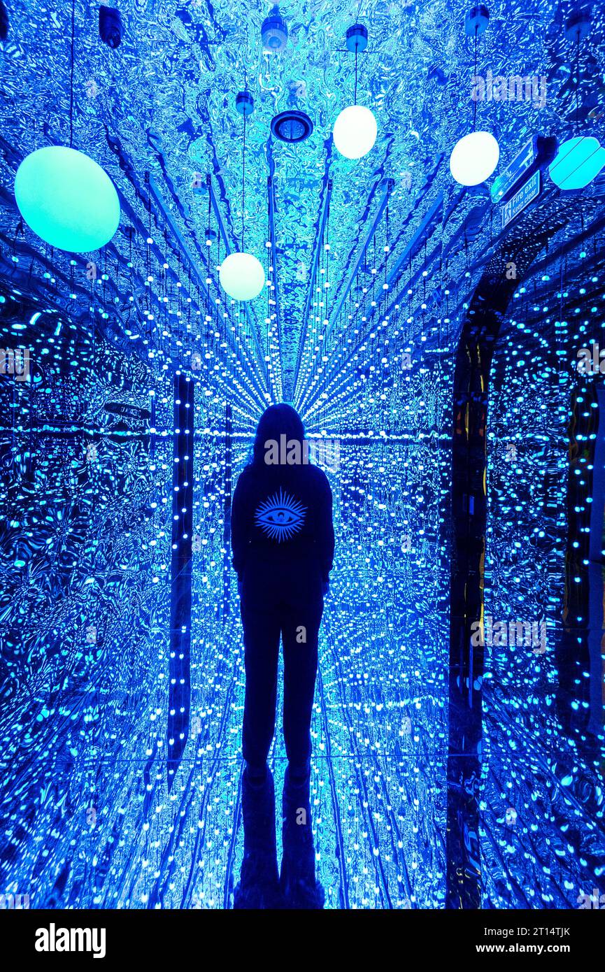 Londres, Royaume-Uni. 11 octobre 2023. Un membre du personnel à l'entrée de l'espace de la galerie avant un aperçu de latent Spaces, une nouvelle exposition immersive chez Illuvisionaries à Crossrail place, Canary Wharf. Le spectacle, de Markos Kay, artiste multidisciplinaire handicapé, qui utilise l’animation et l’intelligence artificielle pour brouiller les frontières entre réalité et illusion, ouvre au public le 14 octobre. Crédit : Stephen Chung / Alamy Live News Banque D'Images