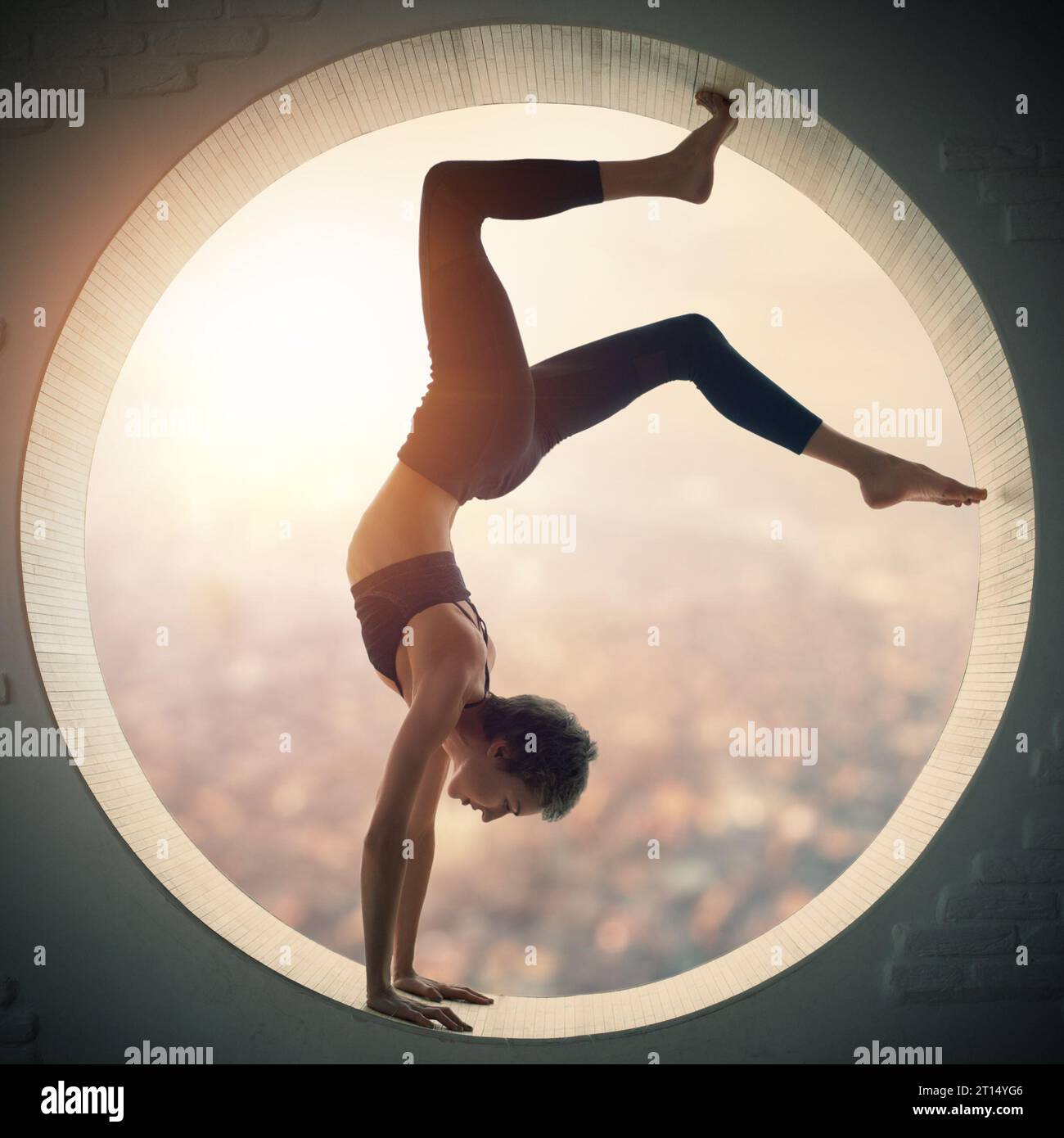 Belle coupe sportive yogi femme pratique yoga handstand asana Bhuja Vrischikasana - Scorpion handstand pose dans une fenêtre ronde avec vue arial de la Banque D'Images