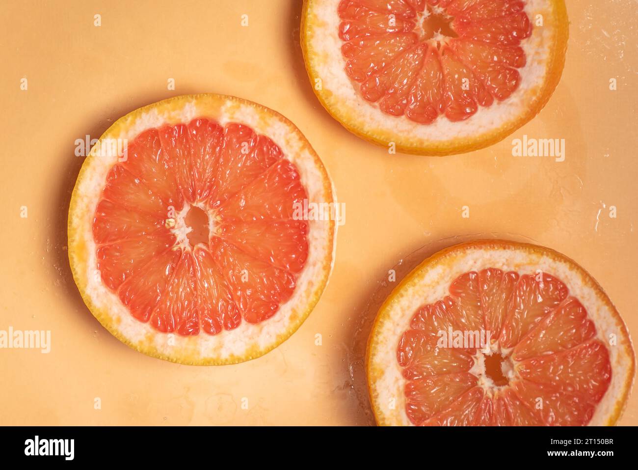 Tranches juteuses de pamplemousse sur fond orange Banque D'Images