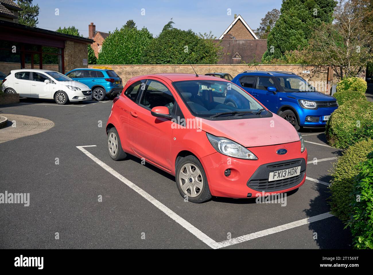 Peinture rouge décolorée, connue sous le nom de photodégradation. Décoloration clairement visible sur la voiture montrant l'effet du soleil sur la peinture rouge qui est la plus sensible Banque D'Images