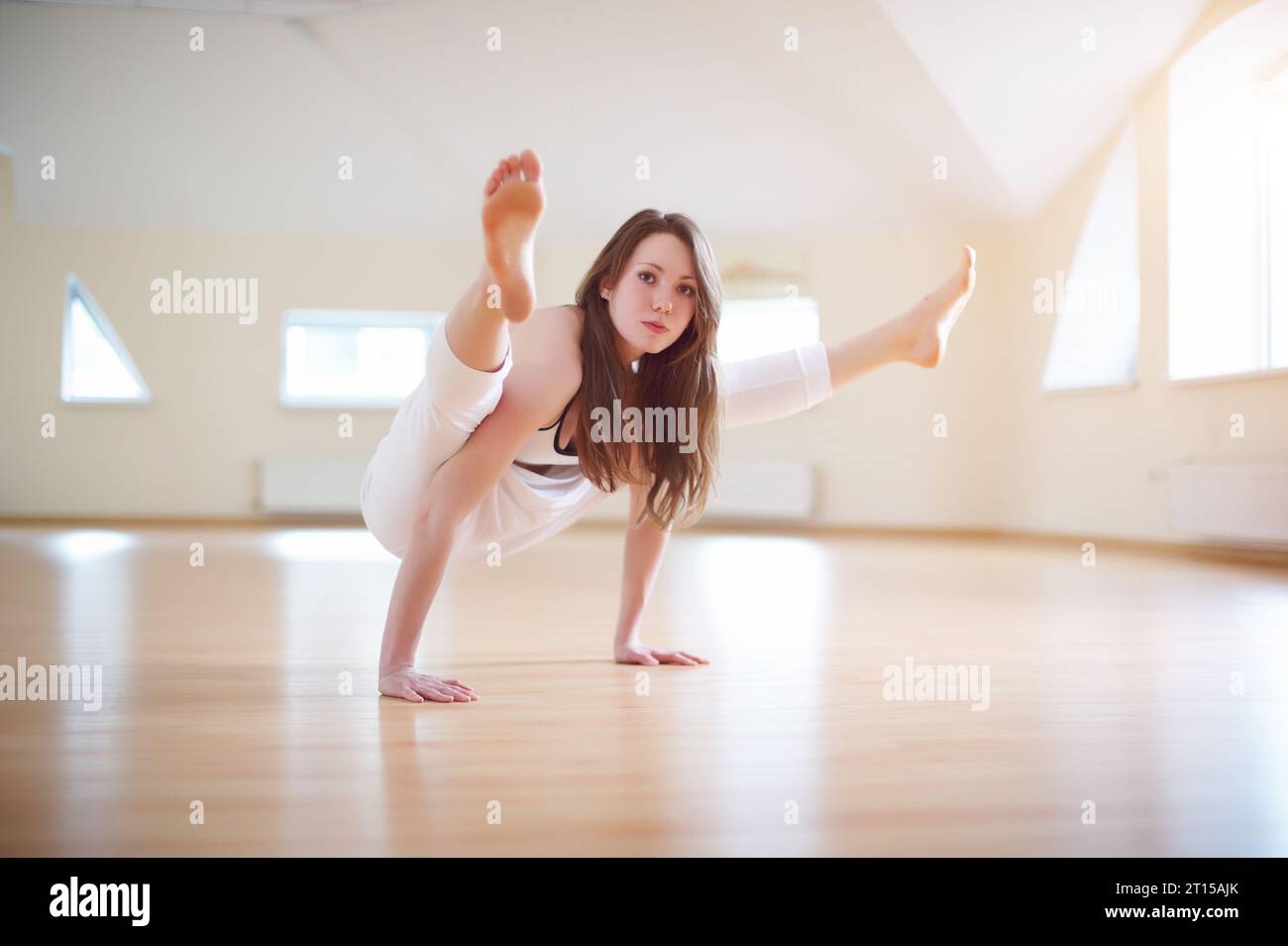 Belle femme pratique handstand yoga asana Tittibhasana - luciole pose dans le studio de yoga. Banque D'Images