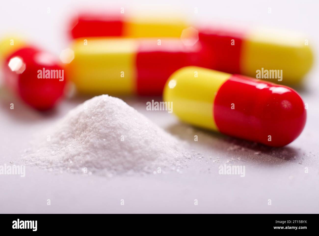 médicaments en poudre blanche avec des capsules rouges jaunes sur fond blanc gros plan Banque D'Images