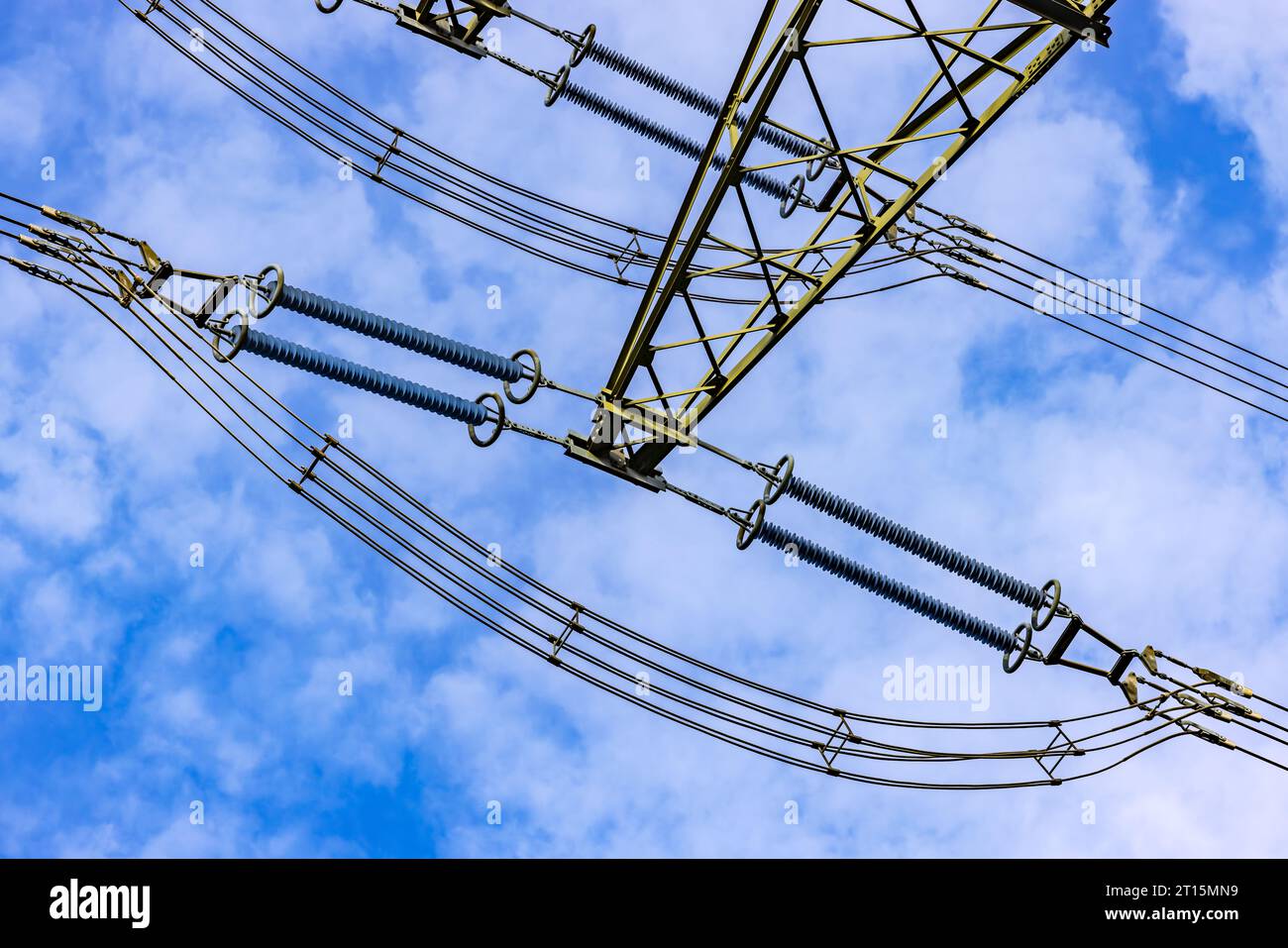 Lignes pour l'électricité avec isolateurs et câbles sur un pylône haute tension comme une vue vers le haut contre le ciel bleu Banque D'Images