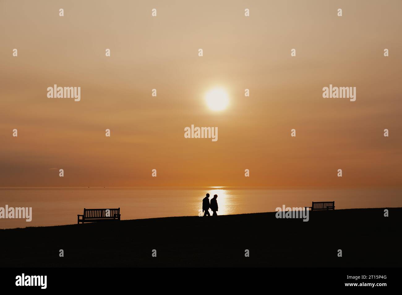 Deux hommes marchant le long des liens à Whitley Bay alors que le soleil se lève Banque D'Images