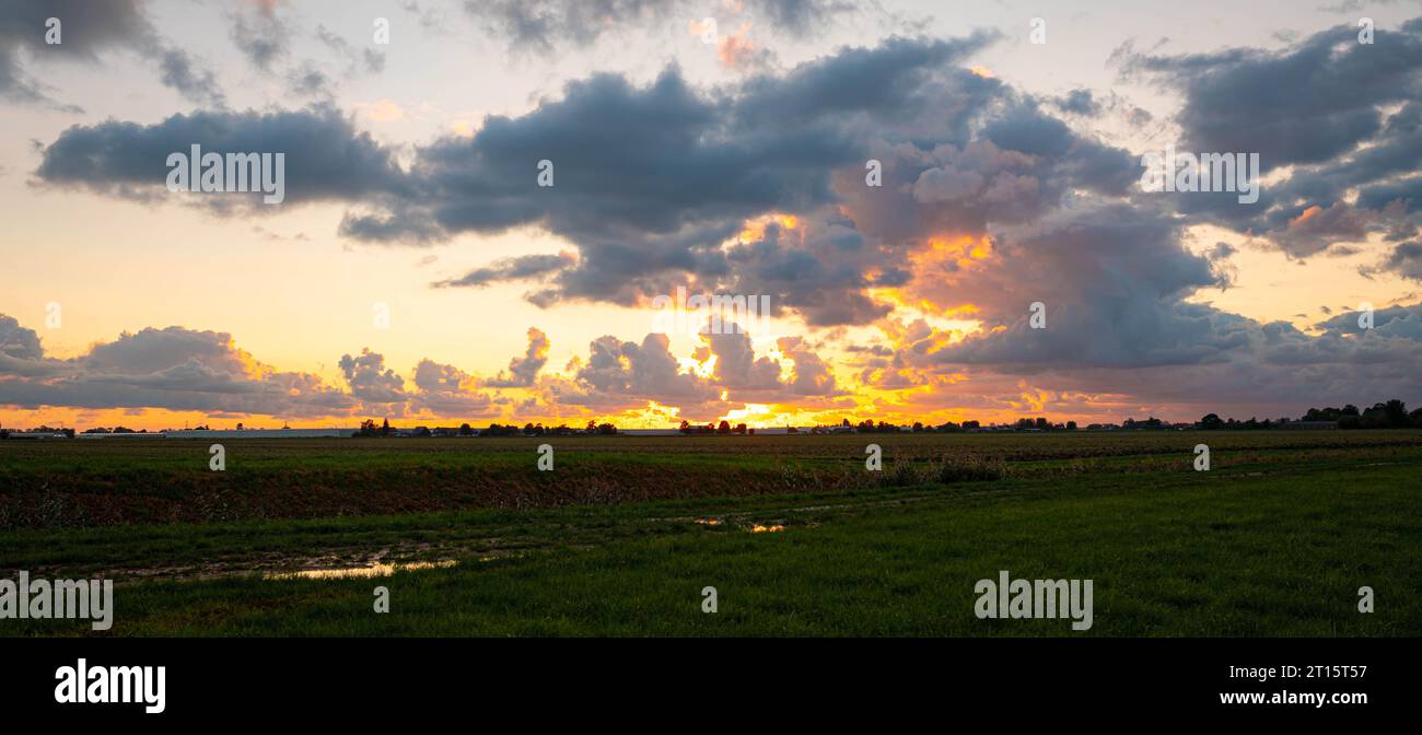 Vue panoramique des nuages de couleur or avec des contours argentés lors d'un coucher de soleil sur la campagne hollandaise. Banque D'Images