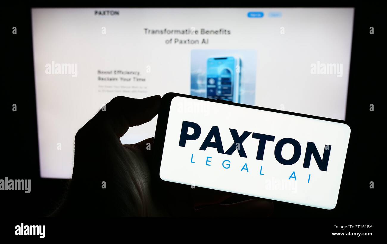 Personne tenant un téléphone portable avec le logo de la société américaine d'intelligence artificielle juridique Paxton ai Inc. Devant la page Web. Concentrez-vous sur l'affichage du téléphone. Banque D'Images