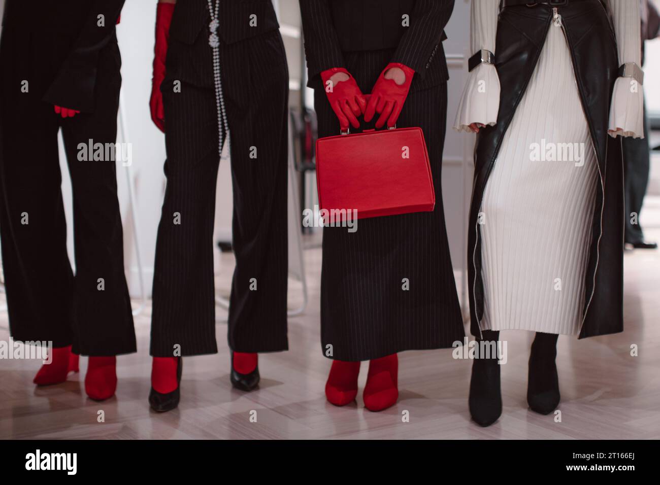 Détails de mode d'une robe blanche chaude tricotée, gants en cuir rouge, sac à main et tenues noires. Mannequins posant sur les coulisses Banque D'Images