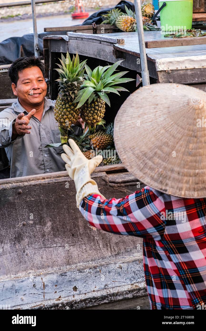 Scène du marché flottant de Fong Dien, près de CAN Tho, Vietnam. Le vendeur d'ananas jette des ananas à son client. Banque D'Images
