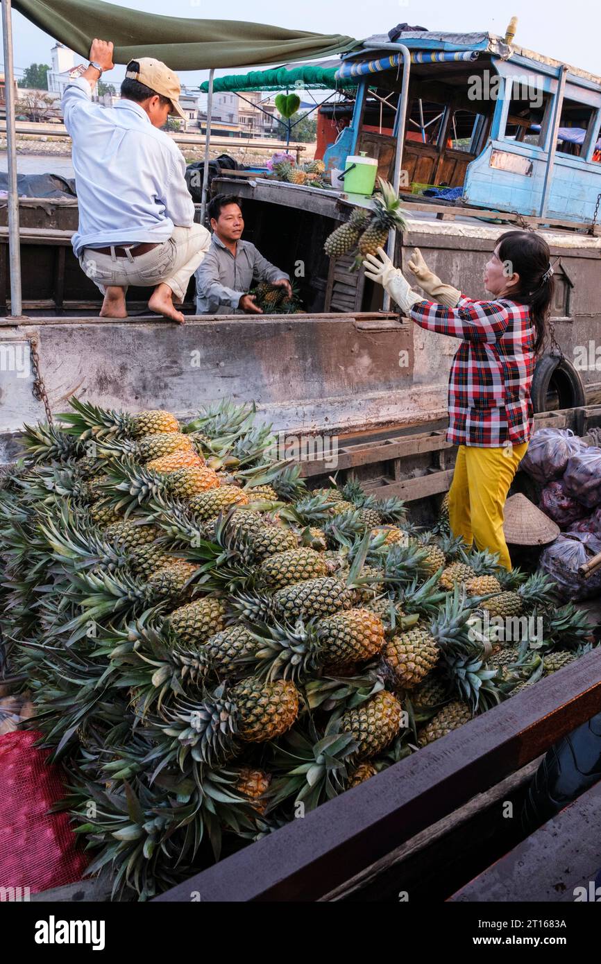 Scène du marché flottant de Fong Dien, près de CAN Tho, Vietnam. Le client attrape des ananas jetés par le fournisseur. Banque D'Images