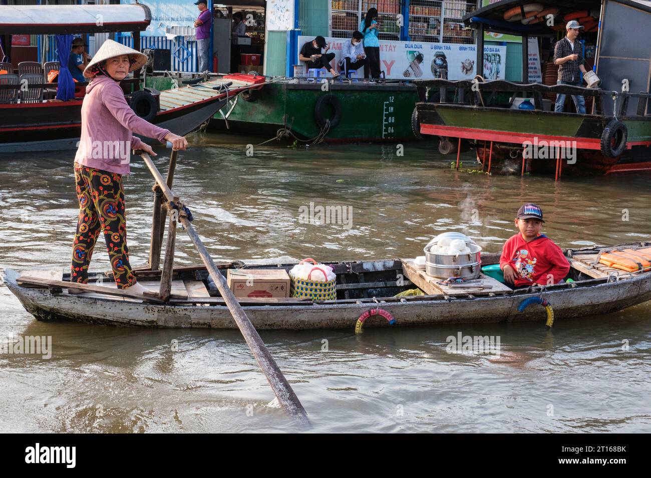 Scène du marché flottant de Fong Dien, près de CAN Tho, Vietnam. Vendor of Breakfast Items circule avec son fils parmi les bateaux transportant des touristes. Banque D'Images