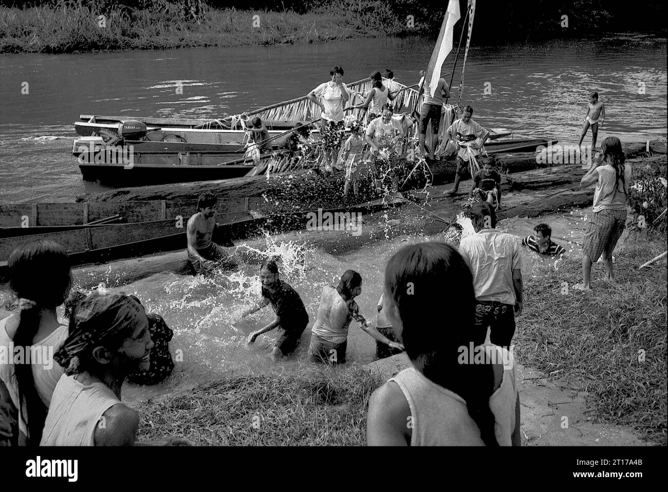 Kalimantan occidental, Indonésie. Mars 2007. Les gens s'éclaboussent d'eau, un acte purifiant, comme un bateau transportant la famille du nouveau chef traditionnel de la communauté de maison longue Dayak Tamambaloh arrive, après une visite à un cimetière voisin où l'ancien chef est enterré, dans le village de Sungai Uluk Palin (Sungulo Palin), Putusibau Utara, Kapuas Hulu, West Kalimantan, Indonésie. la communauté indigène vit dans la plus longue maison longue de Kalimantan, et organise des événements traditionnels en l'honneur de l'ancien chef. plus tard en septembre 2014, leur maison longue a été incendiée par un accident, sans... Banque D'Images