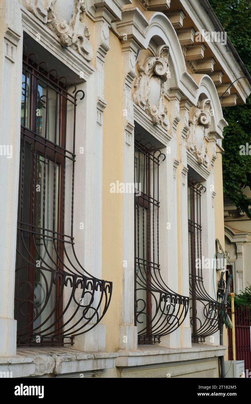 Petite façade de maison dans un style d'architecture ancienne avec corniche décorée de stuc et grilles en fer forgé aux fenêtres à Bucarest, Roumanie Banque D'Images