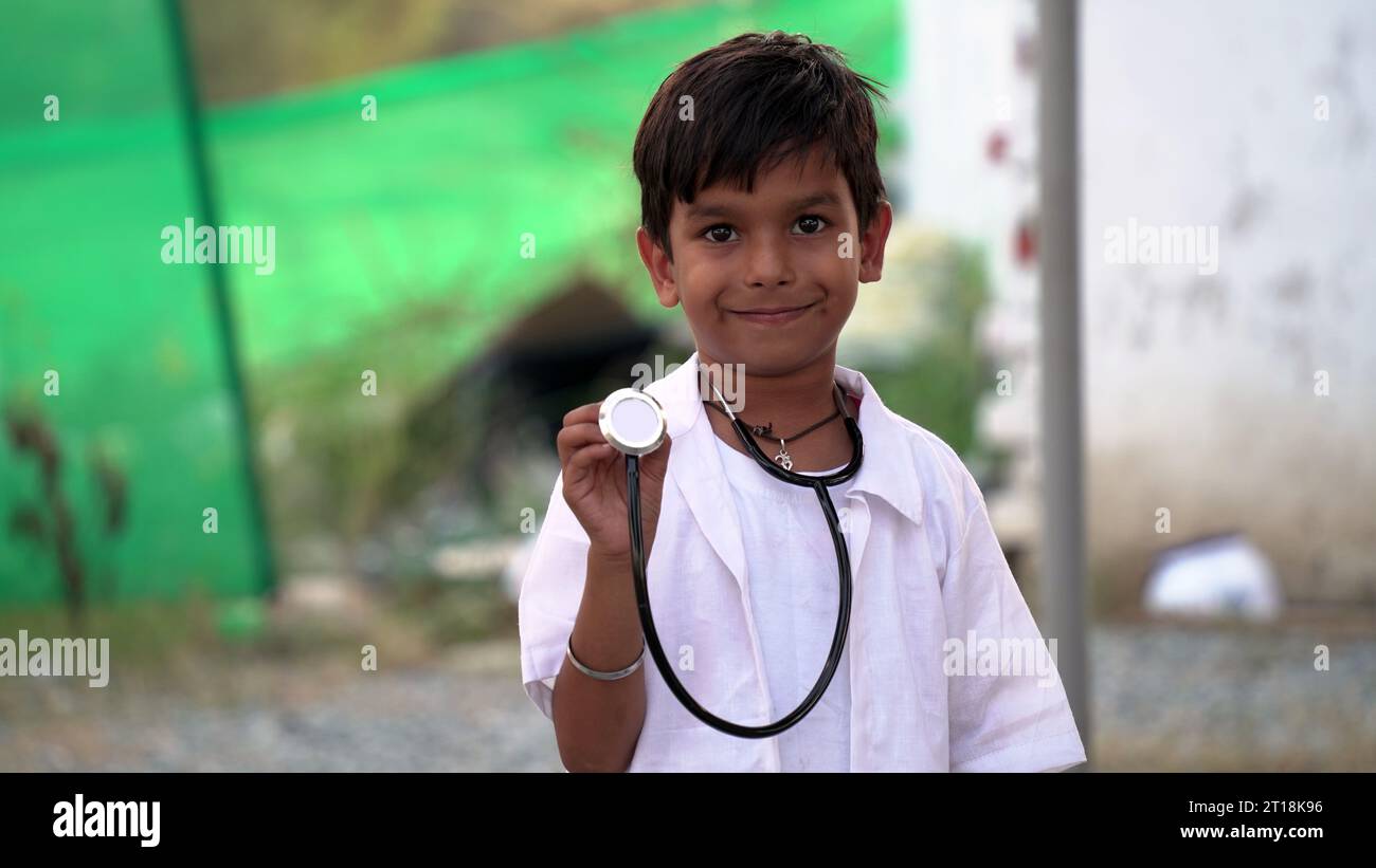 Mignon petit garçon indien porter un uniforme médical tenant stéthoscope jouant le médecin, heureux drôle petit enfant d'âge préscolaire de race mixte prétendant pediatrici Banque D'Images