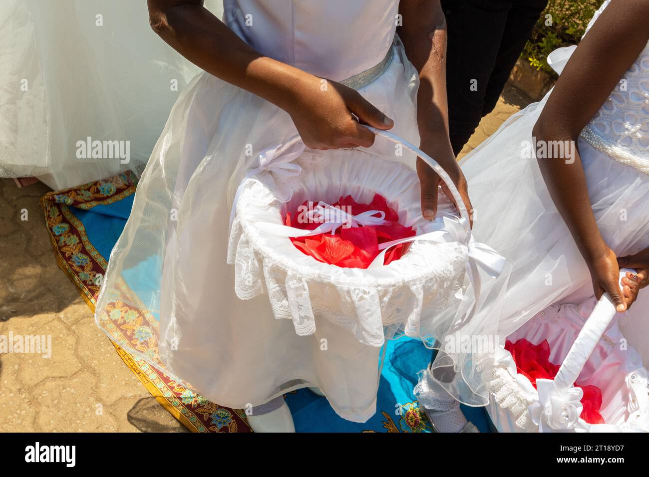 Jeune fille de fleur tenant un panier de fleurs rouges dans une procession de mariage Banque D'Images