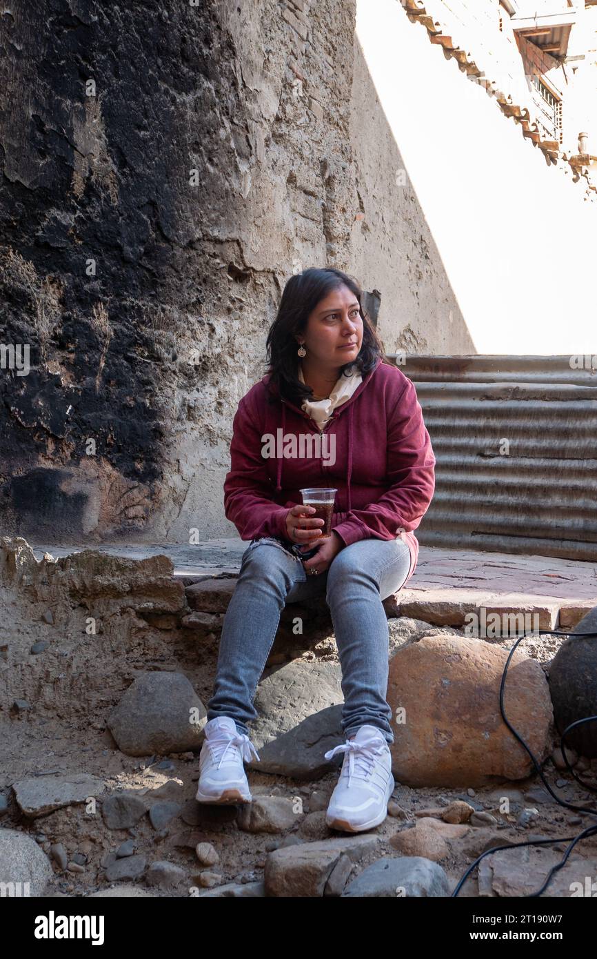 La Paz, Bolivie - août 8 2022 : femme bolivienne assise sur les gradins buvant une boisson chaude d'une tasse en plastique Banque D'Images