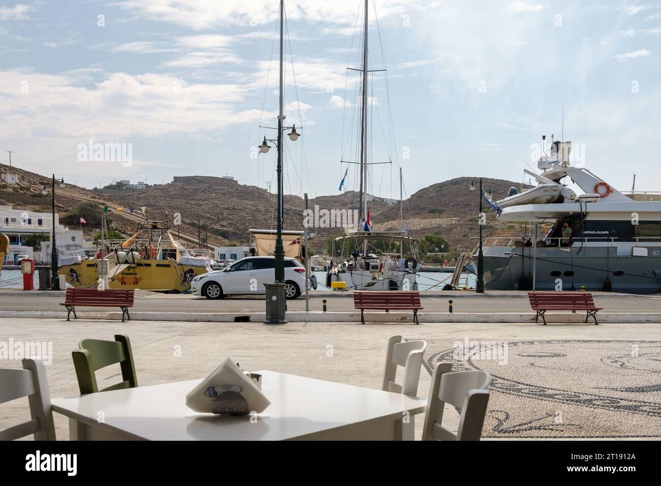 IOS, Grèce - 9 septembre 2023 : vue d'une table de restaurants et de divers bateaux au port d'iOS Grèce Banque D'Images
