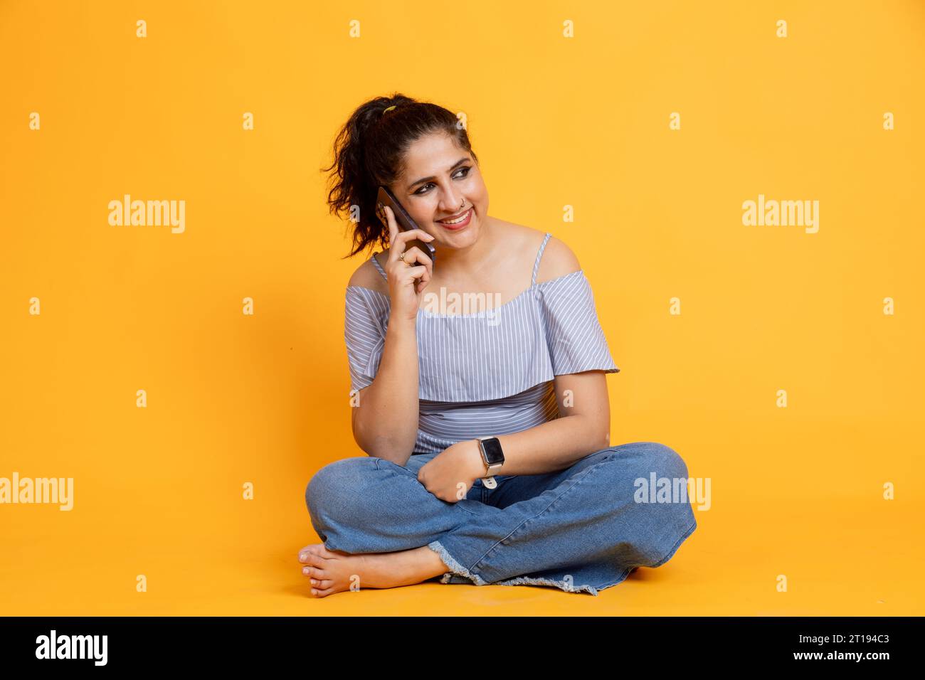 Femme indienne heureuse sur fond isolé parlant au téléphone Banque D'Images