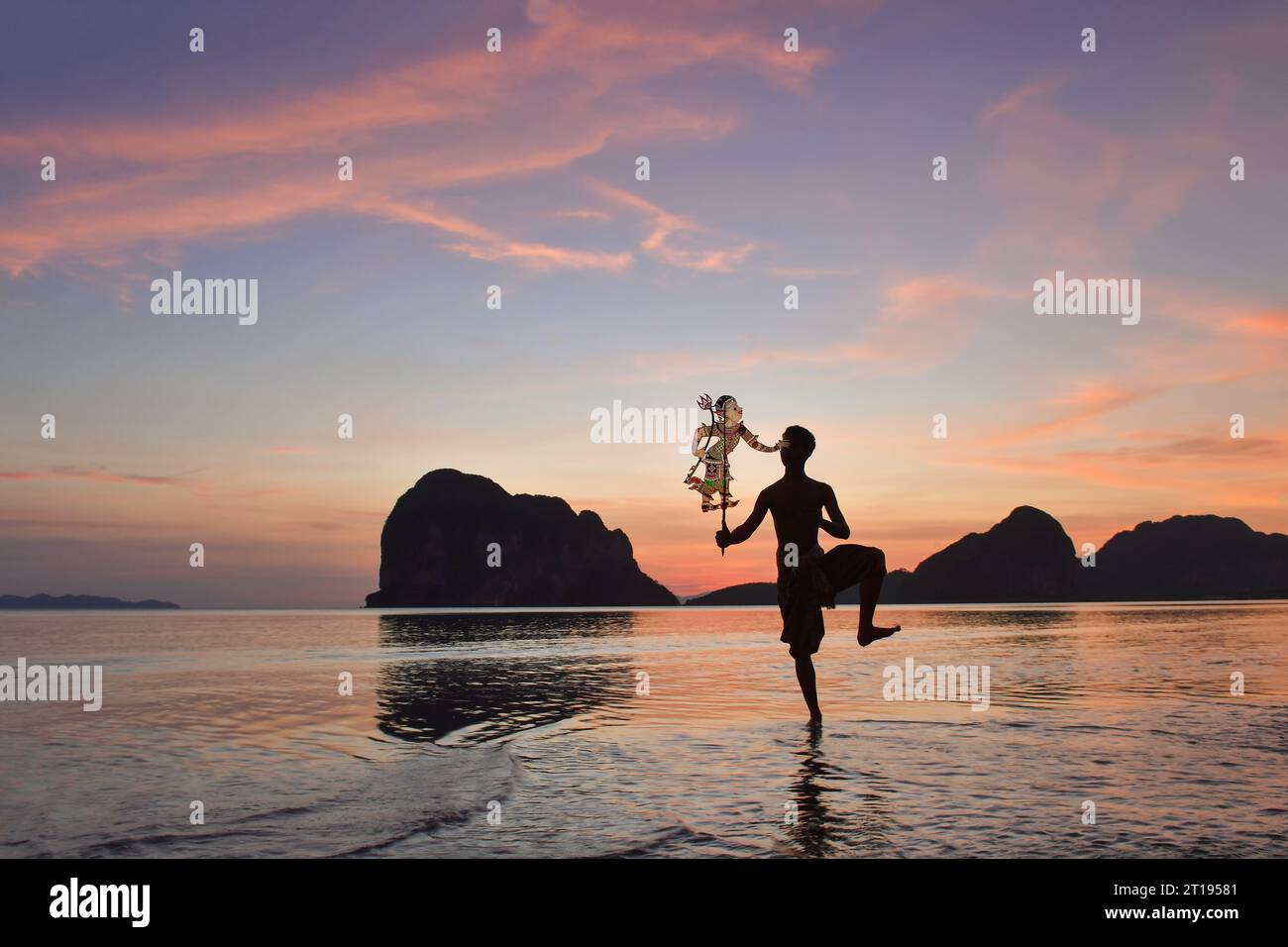 Silhouette d'un homme exécutant le spectacle traditionnel Thai Shadow Puppet Show sur la plage au lever du soleil, Thaïlande Banque D'Images