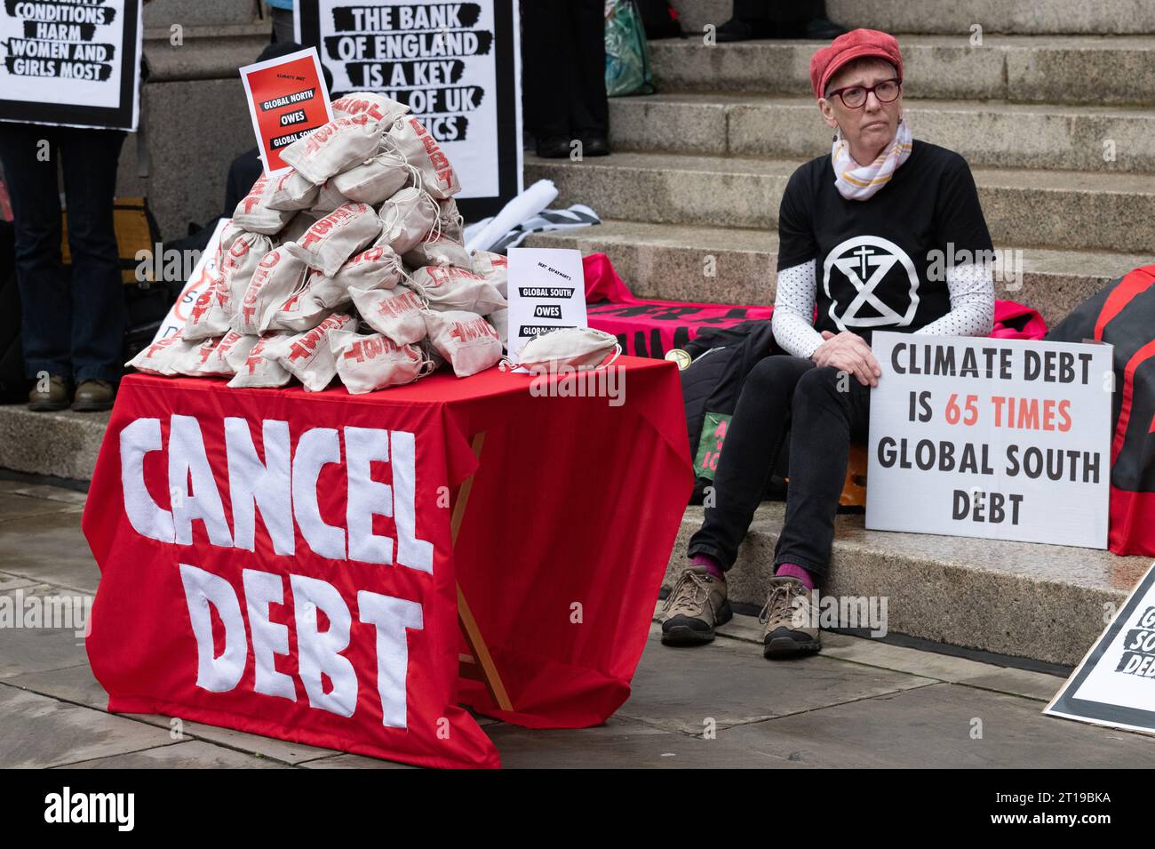 Londres, Royaume-Uni. 12 octobre 2023. Les sacs d'argent symbolisant la dette due par les pays riches aux plus pauvres, et vice versa, reposent sur une table près de la Banque d'Angleterre en tant que coalition de groupes, y compris Debt for Climate, extinction Rebellion et Christian Climate action organisent un rassemblement appelant à l'annulation de la dette détenue par les nations du Sud pour des raisons de justice et comme condition préalable pour qu'elles combattent et s'adaptent au changement climatique. Cette action a coïncidé avec les réunions annuelles du Groupe de la Banque mondiale et du FMI qui ont eu lieu au Maroc. Crédit : Ron Fassbender/Alamy Live News Banque D'Images