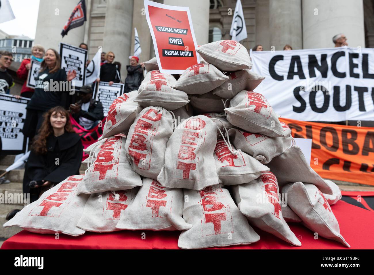 Londres, Royaume-Uni. 12 octobre 2023. Les sacs d'argent symbolisant la dette due par les pays riches aux plus pauvres, et vice versa, reposent sur une table près de la Banque d'Angleterre en tant que coalition de groupes, y compris Debt for Climate, extinction Rebellion et Christian Climate action organisent un rassemblement appelant à l'annulation de la dette détenue par les nations du Sud pour des raisons de justice et comme condition préalable pour qu'elles combattent et s'adaptent au changement climatique. Cette action a coïncidé avec les réunions annuelles du Groupe de la Banque mondiale et du FMI qui ont eu lieu au Maroc. Crédit : Ron Fassbender/Alamy Live News Banque D'Images