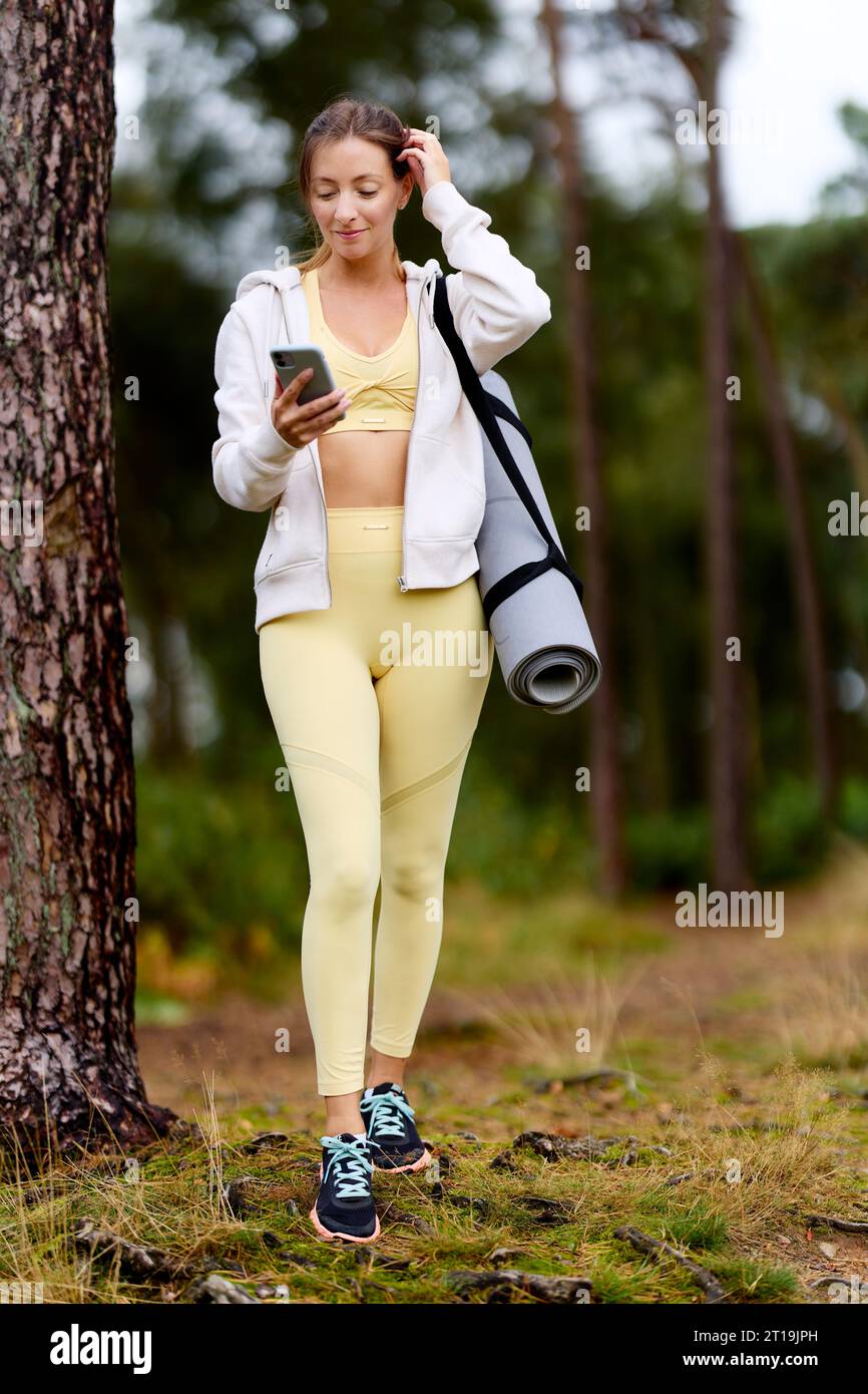 Femme marchant à l'extérieur regardant son téléphone Banque D'Images