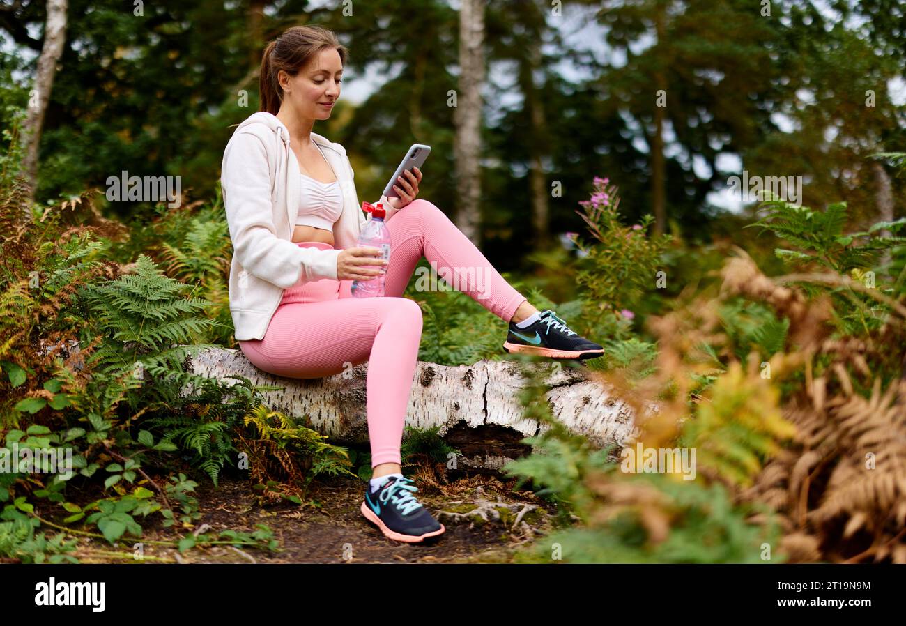 Femme marchant à l'extérieur regardant son téléphone Banque D'Images