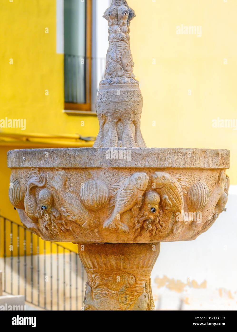Fontaine médiévale en pierre dans une petite place. L'objet ancien a été récemment restauré et il montre des décorations en bas relief. Banque D'Images