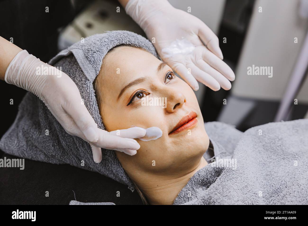 Femme massage facial traitement de la peau du visage avec la crème hydratante d'extrait de plantes d'essence naturelle dans la clinique de spa de beauté. Banque D'Images