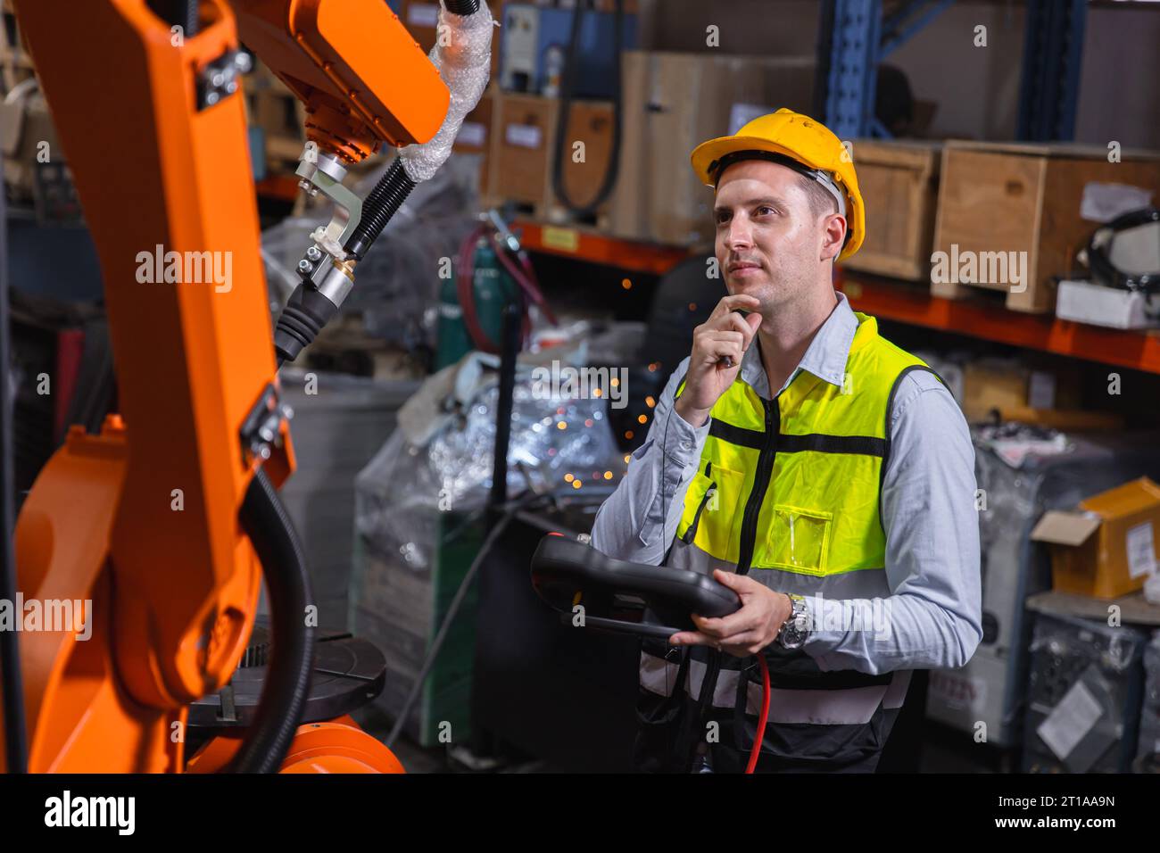 L'ingénieur caucasion mâle de service de travail fixe actionner le bras automatique de soudage de robot avec la pensée de question résolvant l'expression de problème Banque D'Images