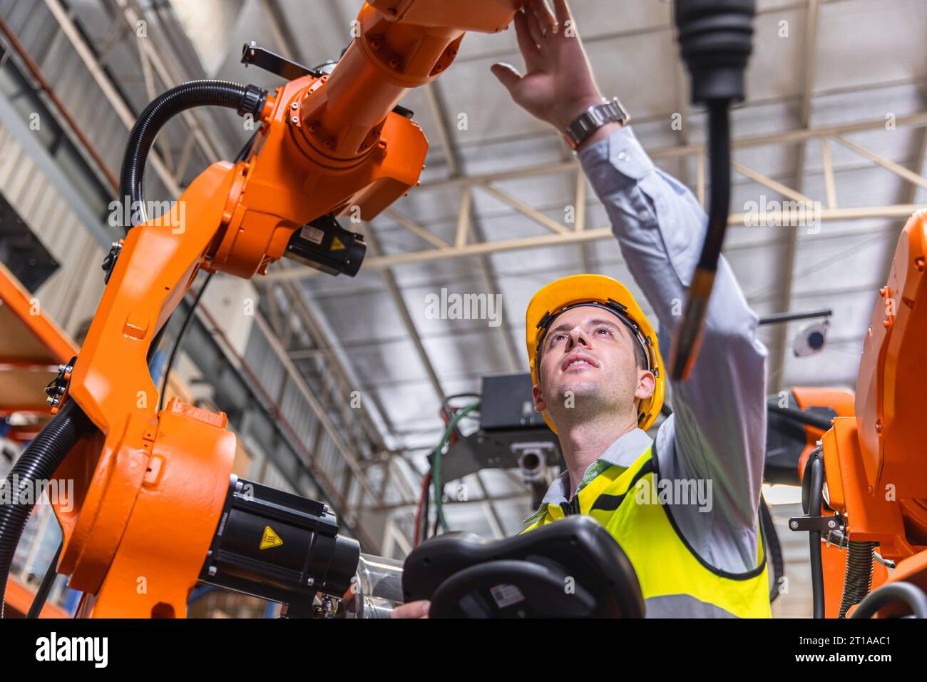 Homme d'ingénieur moderne intelligent utilisant la technologie de robot moderne. Installation de bras de soudage robotisé dans le processus de production d'automatisation en usine Banque D'Images