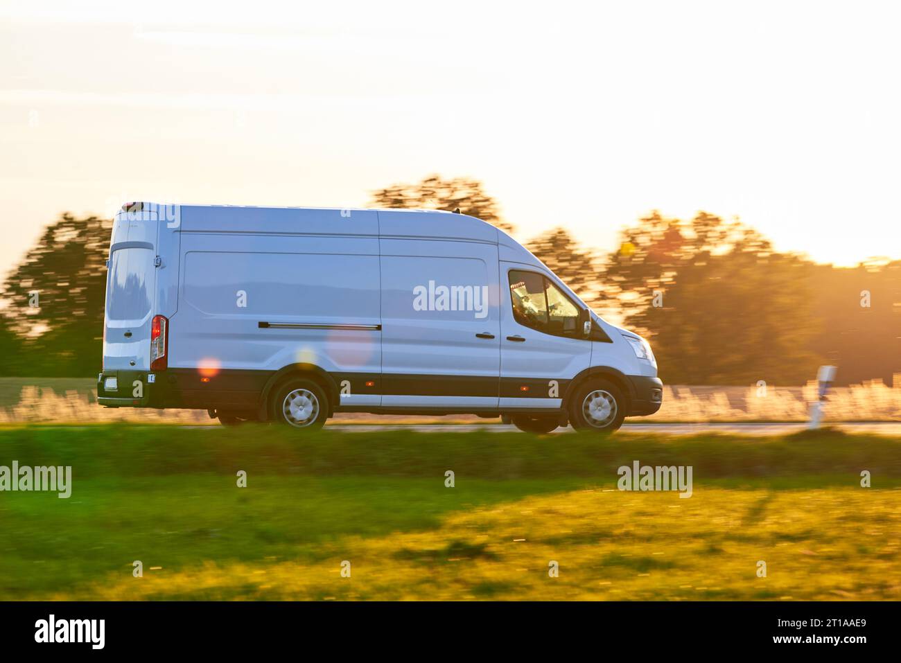 White Van conduisant rapidement sur une route de campagne. Livraison Van conduisant au coucher du soleil en saison d'automne. Banque D'Images