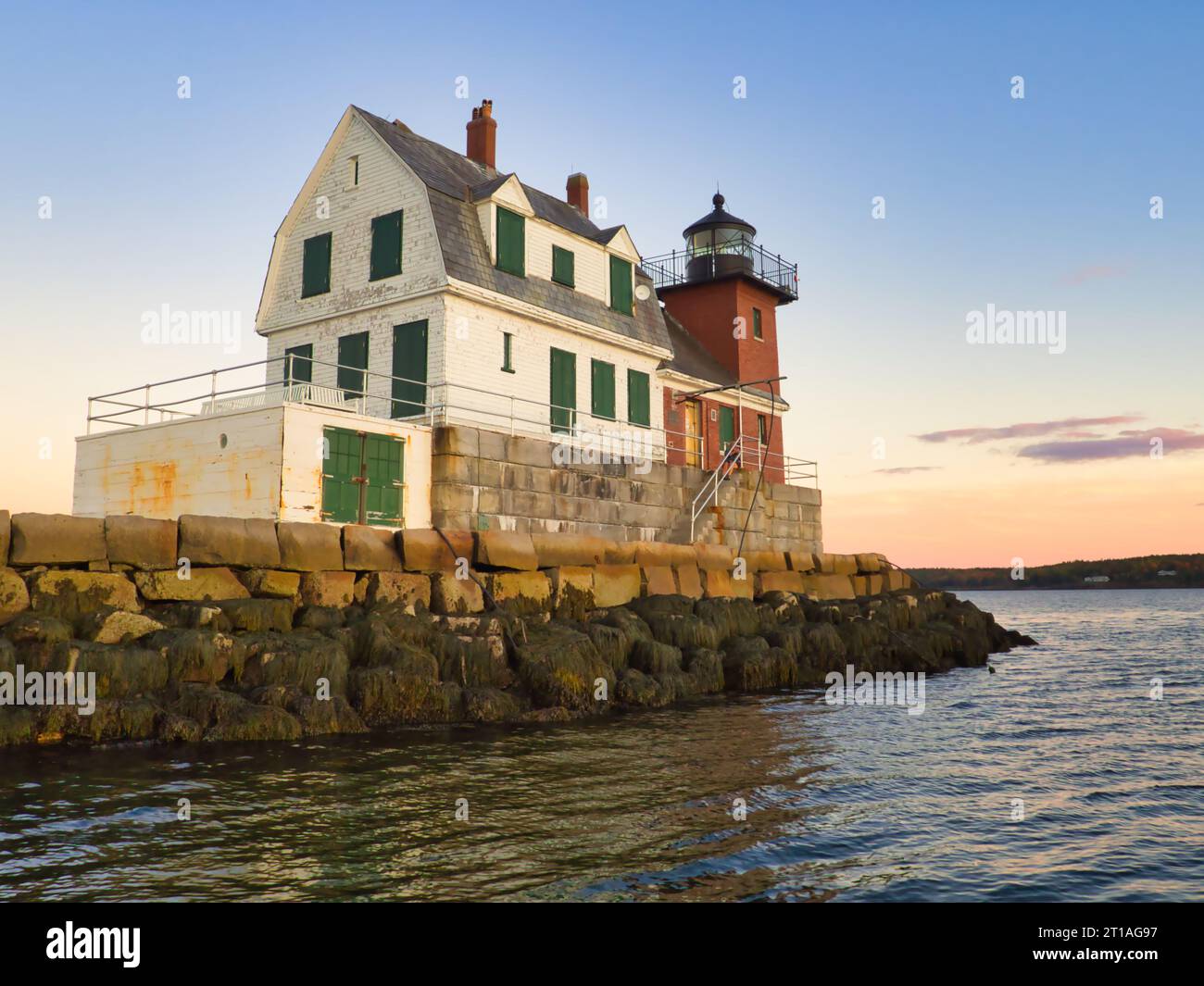 Coucher de soleil à l'automne au Rockland Breakwater Lighthouse dans le Maine vu de l'eau. Bâtiment historique avec architecture en bois, pierre et brique. Banque D'Images