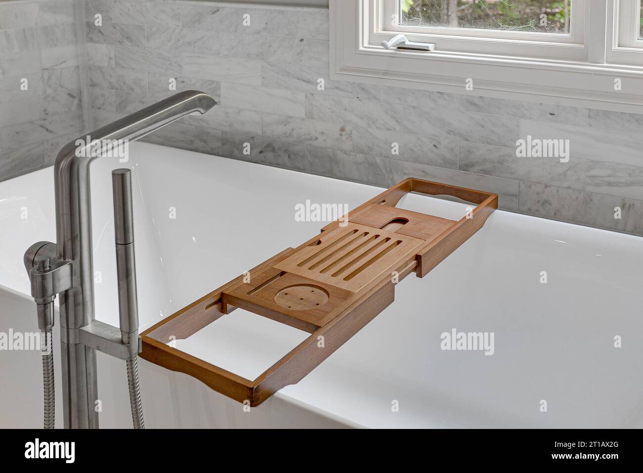Relaxant calme Luxury salle de bains moderne baignoire intérieure avec plateau en bambou pour livres et gommages. Murs et planchers en carreaux de pierre. Banque D'Images