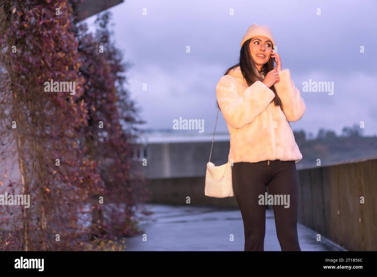 Jeune jolie brunette caucasienne marchant dans la ville en hiver, portant un pull en laine rose Banque D'Images